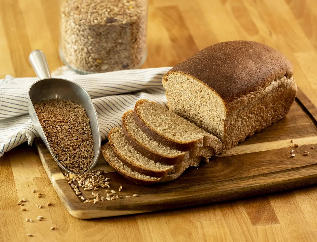 A fresh-milled loaf beside a scoop of whole wheat berries